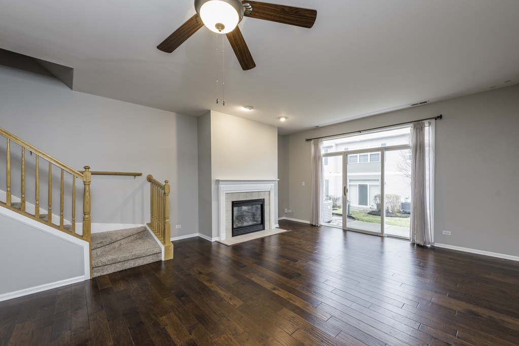 2879 Falling Waters Drive, Unit 2879 Lindenhurst, IL 60046 - Photo 3 of 30 an empty room with wooden floor fireplace and windows