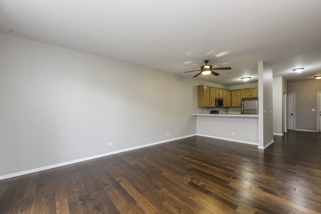 2879 Falling Waters Drive, Unit 2879 Lindenhurst, IL 60046 - Photo 5 of 30 wooden floor in an empty room with a kitchen