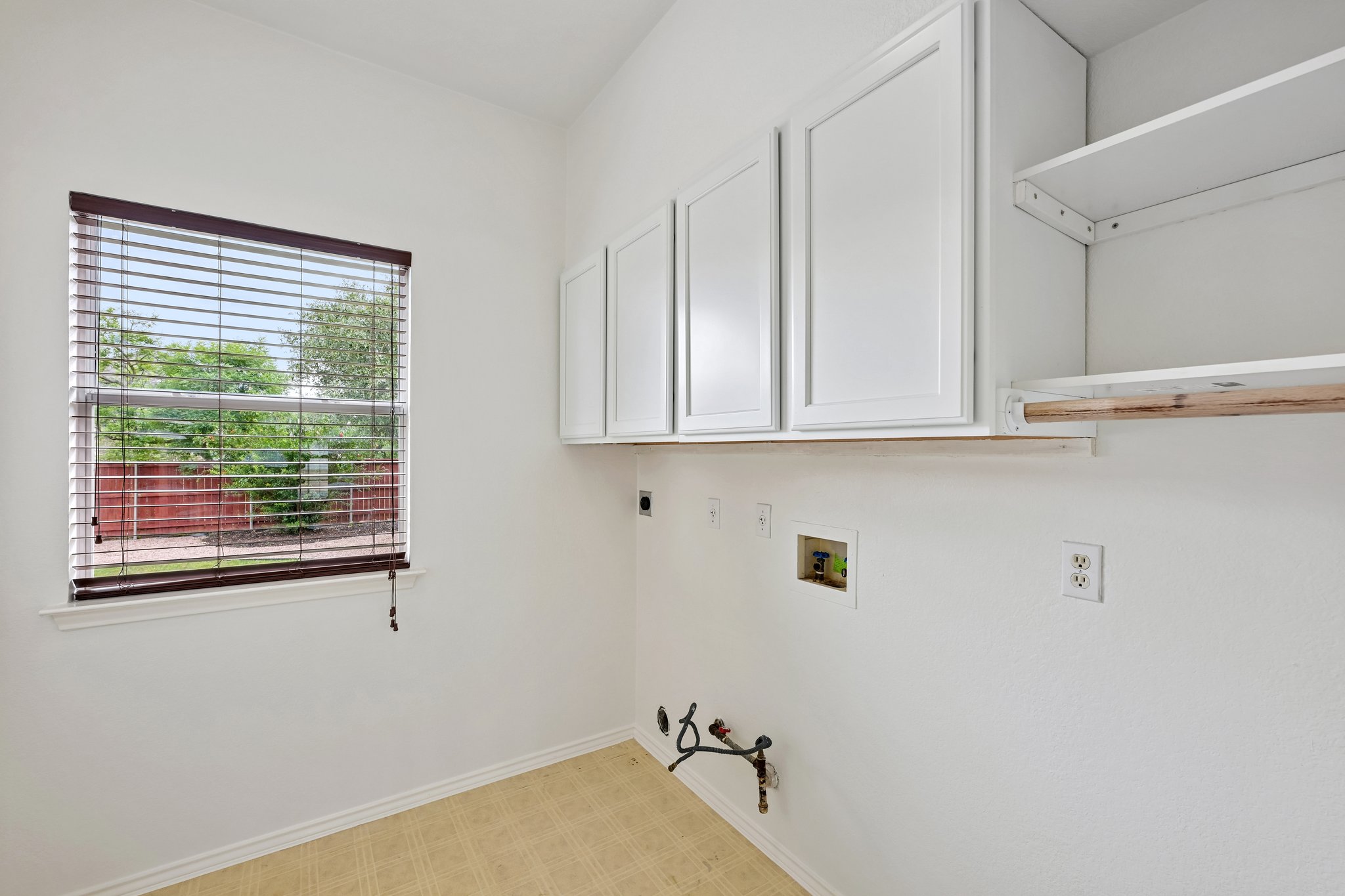 4100 Mocha Trail Austin, TX 78728 - Photo 24 of 33 Functional laundry space with storage cabinets and a window offering a green garden view.