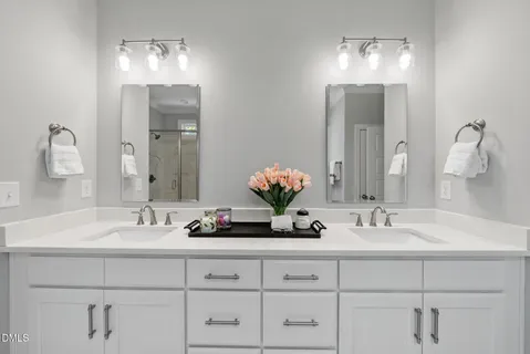a spacious bathroom with a double vanity sink a large mirror and shower