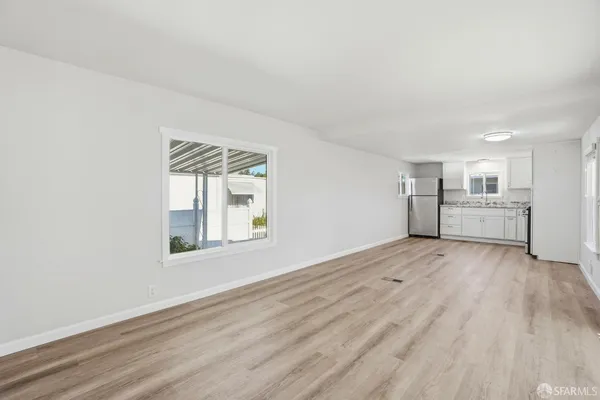 a view of an empty room with a kitchen and a window