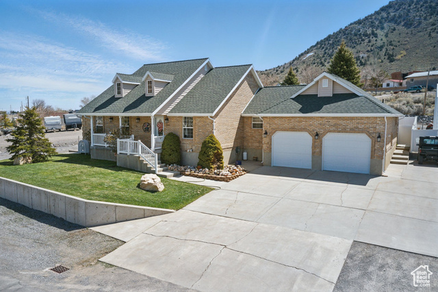 151 South Haulage Road Eureka, UT 84628 - Photo 5 of 36 View of front of home with a shingled roof, a front lawn, brick siding, concrete driveway, and covered porch