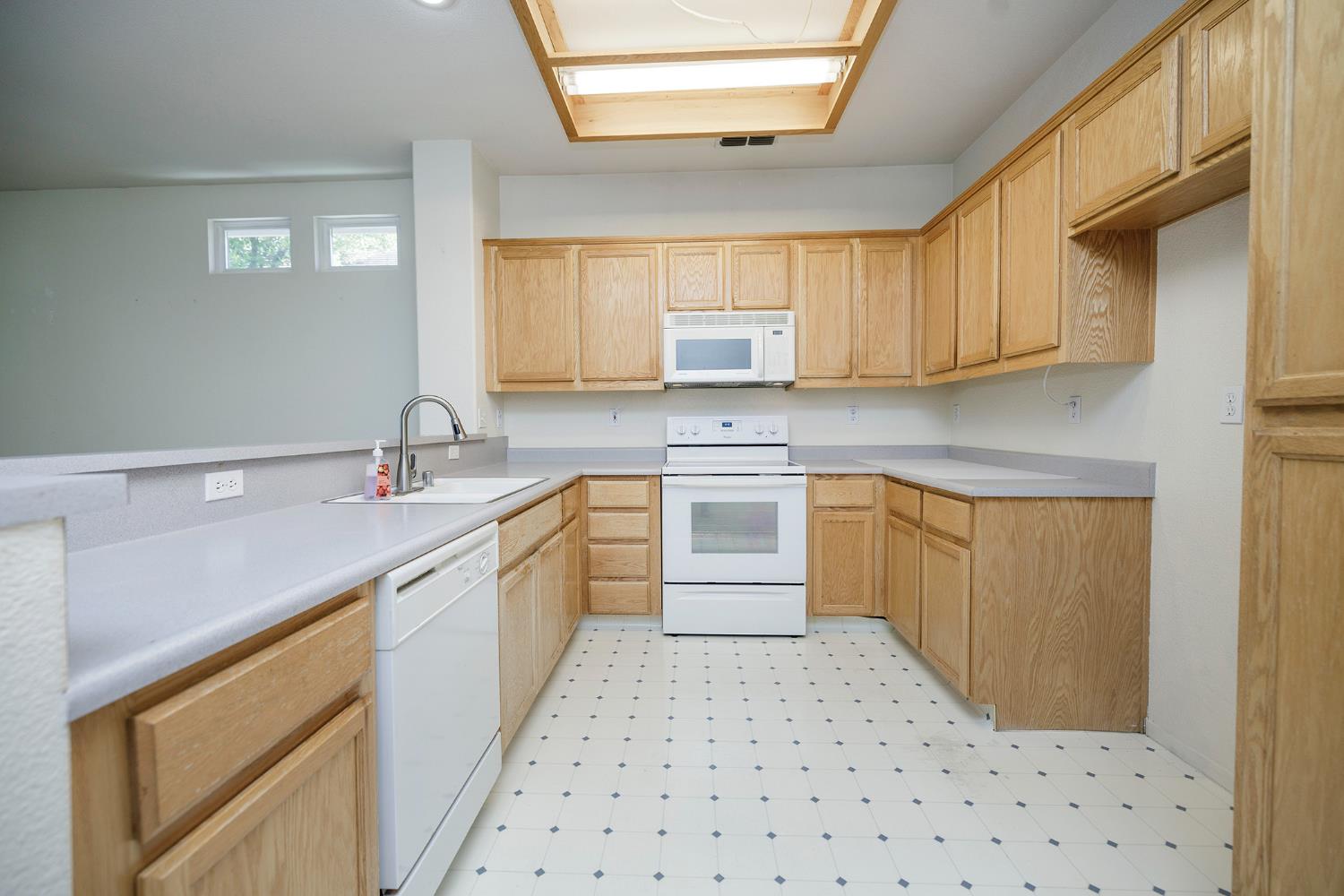 2123 Spring Blossom Lane Turlock, CA 95382 - Photo 11 of 44 a kitchen with a sink a stove top oven and white cabinets
