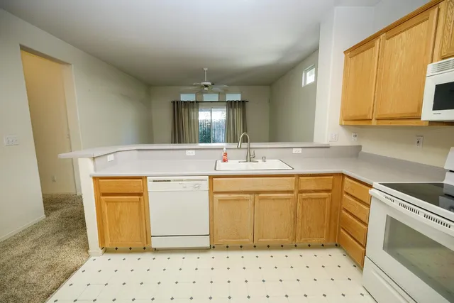 a white kitchen with a sink window and cabinets
