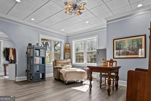 a bedroom with a large bed a chandelier and windows