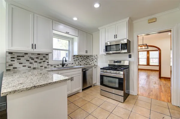 a kitchen with granite countertop a stove sink and microwave