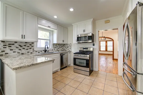 a kitchen with granite countertop a stove sink and refrigerator
