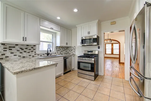 a kitchen with granite countertop a stove sink and refrigerator