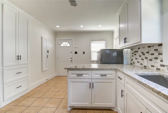 a kitchen with granite countertop white cabinets and stainless steel appliances