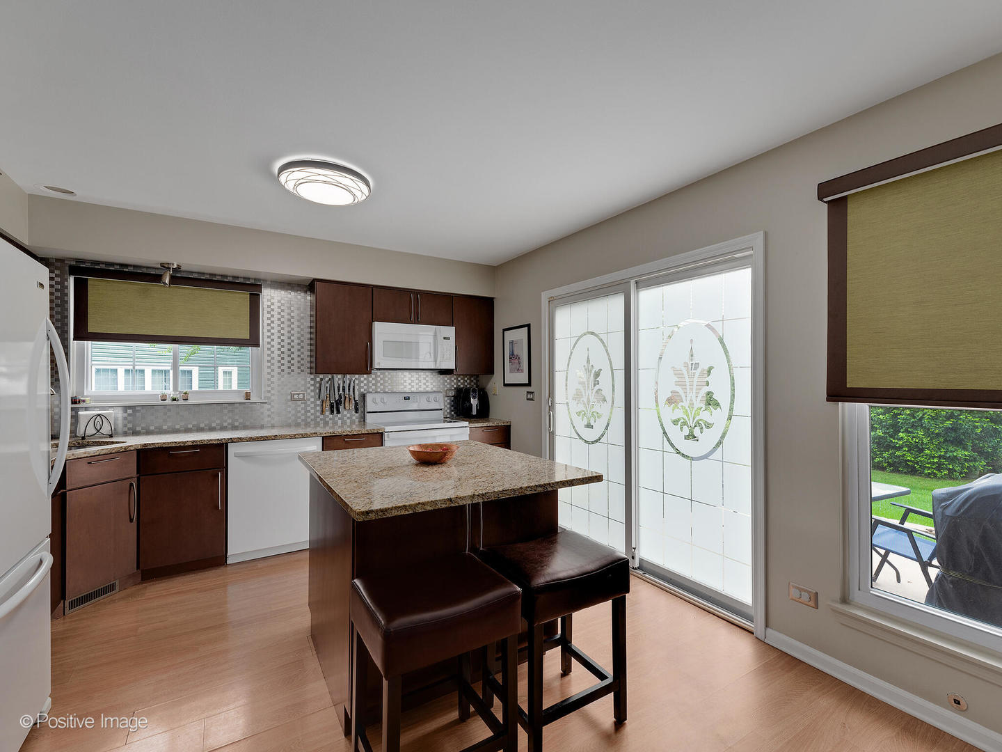 1334 Ridgefield Circle Carol Stream, IL 60188 - Photo 9 of 16 a kitchen with stainless steel appliances granite countertop a stove a refrigerator a sink a dining table and chairs with wooden floor
