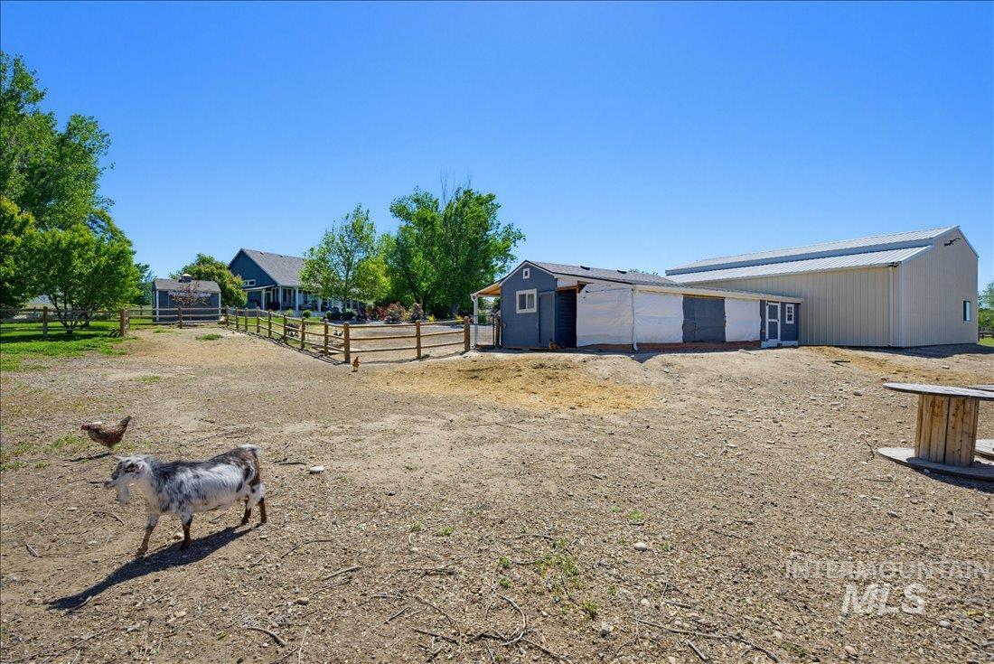 24623 Falcon Lane Caldwell, ID 83607 - Photo 35 of 40 Expansive property featuring a large outbuilding with a metal roof, a smaller blue-sided structure, and a fenced area