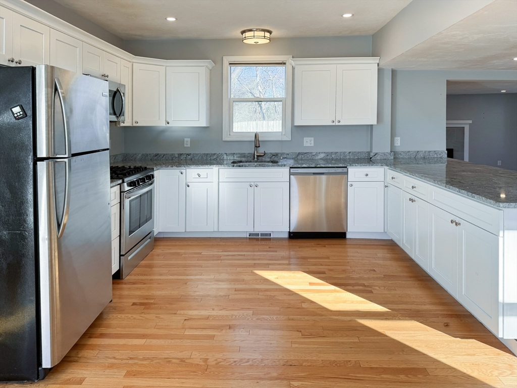 1 Chapel Lane Wareham, MA 02538 - Photo 7 of 29 a kitchen with granite countertop a refrigerator sink and white cabinets
