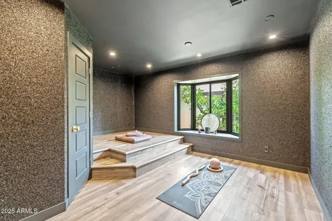 an empty room with wooden floor chandelier fan and windows