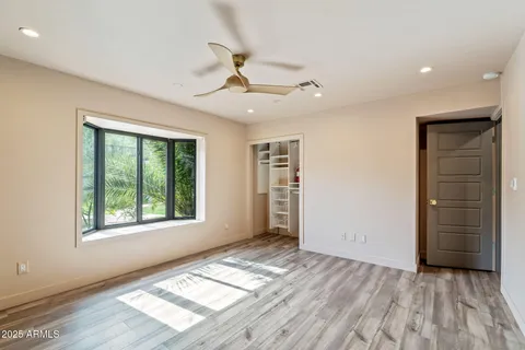 a view of empty room with wooden floor and fan