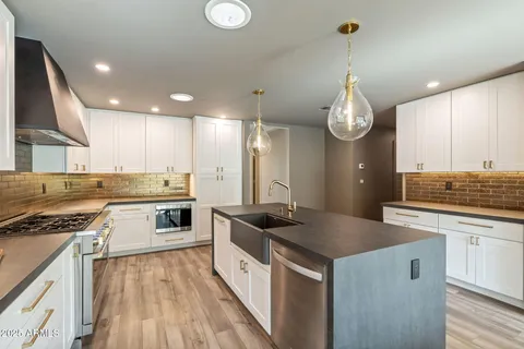 a kitchen with granite countertop a sink stove and cabinets