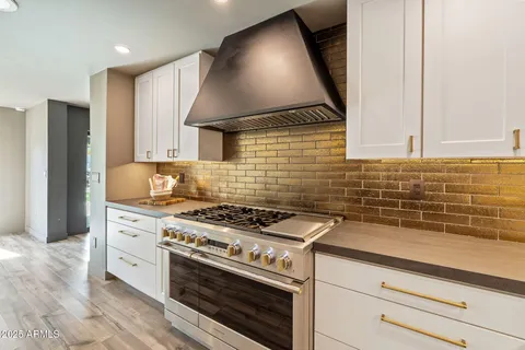 a kitchen with kitchen island granite countertop a stove a sink a center island a stove and a window with wooden floor