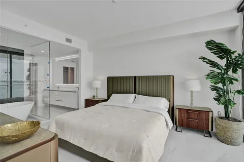 a bedroom with a large bed and a potted plant