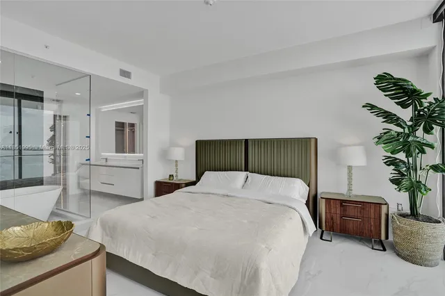 a bedroom with a large bed and a potted plant