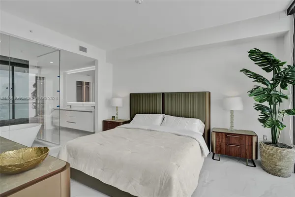 a bedroom with a large bed and a potted plant