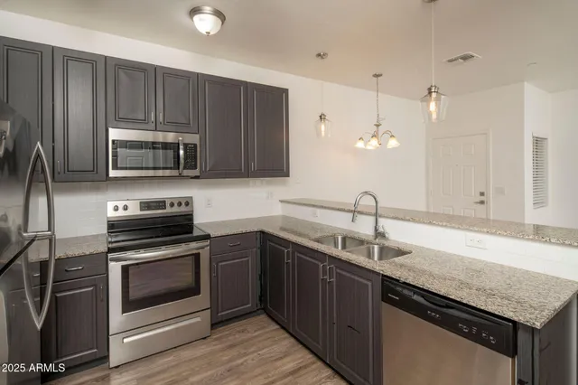 a kitchen with granite countertop a sink cabinets and stainless steel appliances