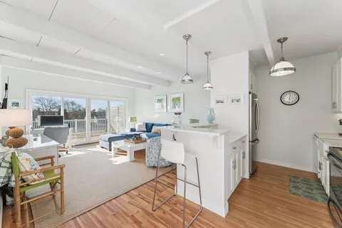 a living room with furniture a large window and wooden floor