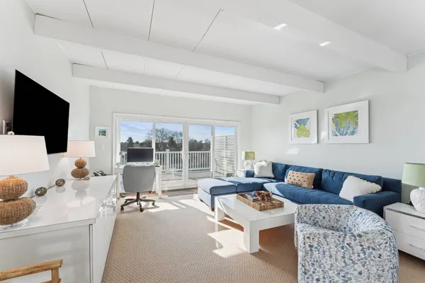 a living room with furniture a flat screen tv and a large window