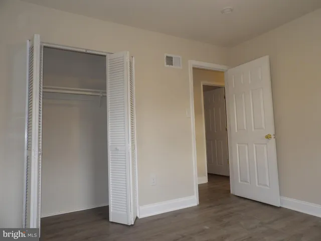 an empty room with wooden floor & closet area