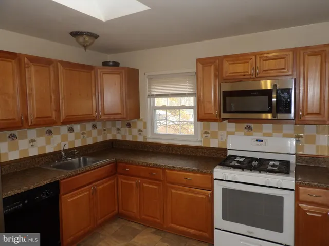a kitchen with granite countertop a sink a stove and microwave