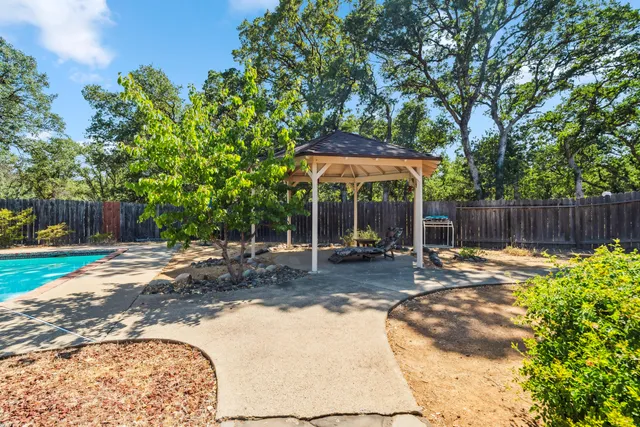 a view of a backyard with table and chairs under an umbrella with wooden fence