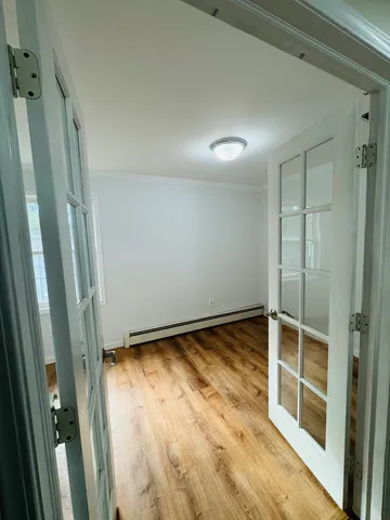a view of empty room with wooden floor and fan