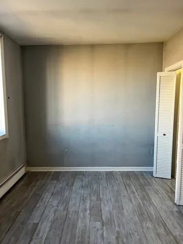 an empty room with wooden floor and white walls