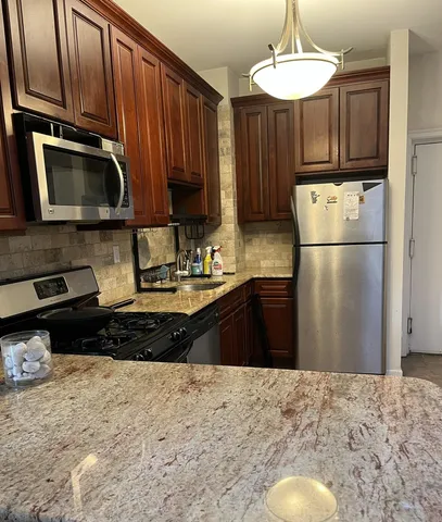 a kitchen with granite countertop a refrigerator stove top oven a sink and dishwasher