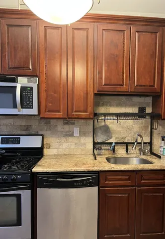 a kitchen with stainless steel appliances granite countertop wooden cabinets a stove top oven