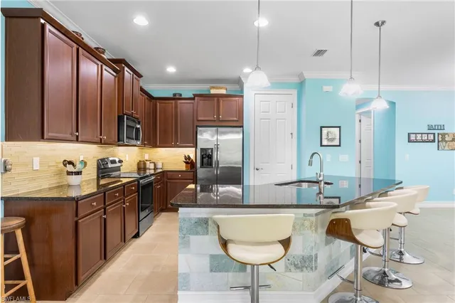 a kitchen with kitchen island granite countertop a sink a counter top space appliances and cabinets