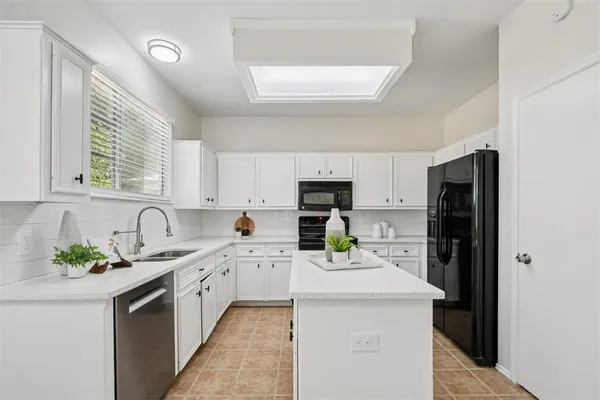 a kitchen with a sink a stove a refrigerator a center island and a window