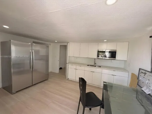 a kitchen with stainless steel appliances granite countertop a stove a sink a refrigerator with white cabinets and wooden floor