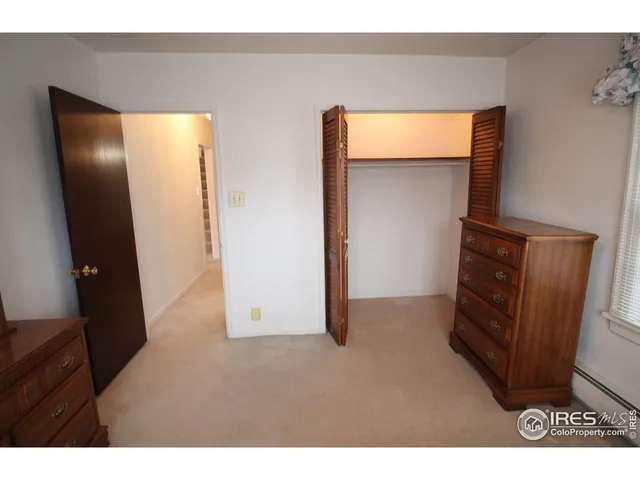 a view of an empty room with wooden floor and closet
