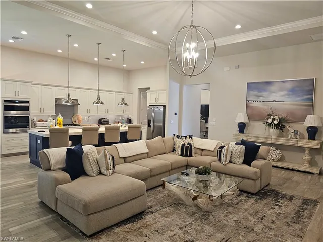 a living room with furniture kitchen view and a chandelier