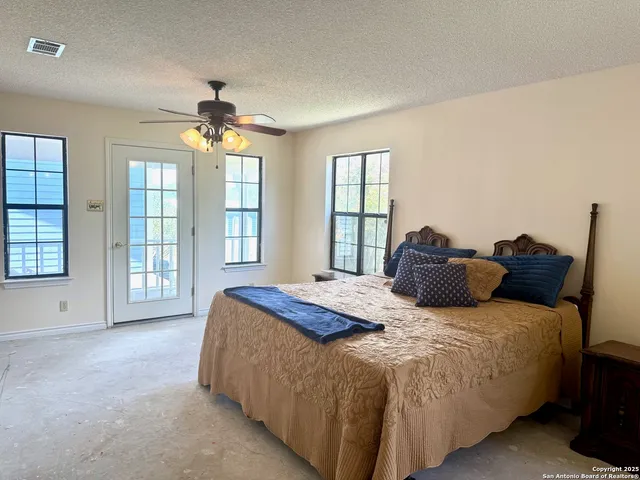 an empty room with windows and ceiling fan