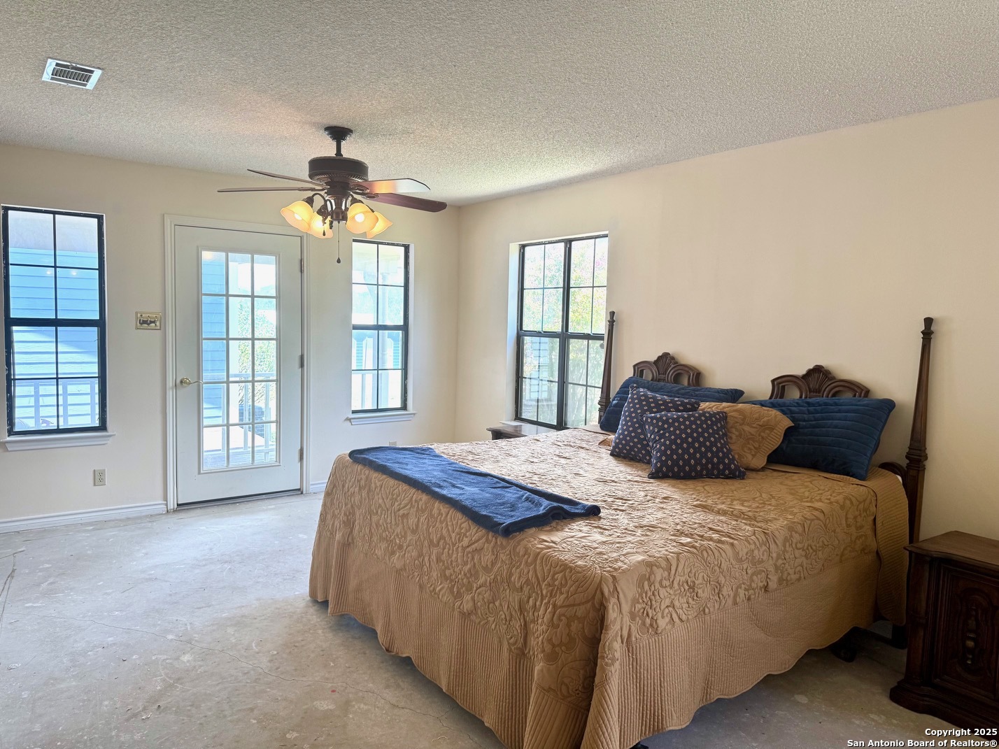 181 Leinweber Drive Leakey, TX 78873 - Photo 17 of 56 a spacious bedroom with a large bed and a chandelier