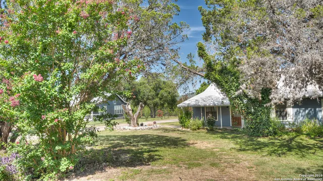 a backyard of a house with table and chairs under an umbrella
