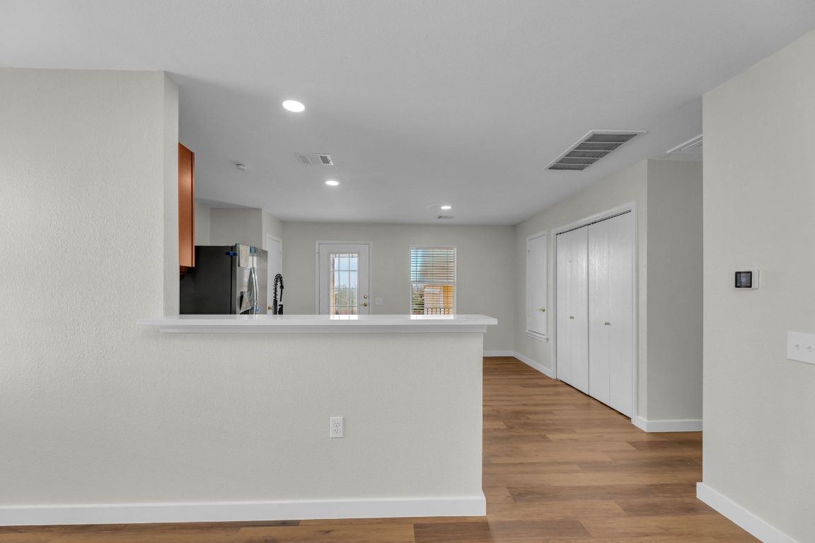 11617 Briarcreek Loop Manor, TX 78653 - Photo 7 of 37 Kitchen with light countertops, light wood-type flooring, stainless steel refrigerator with ice dispenser, recessed lighting, and a peninsula