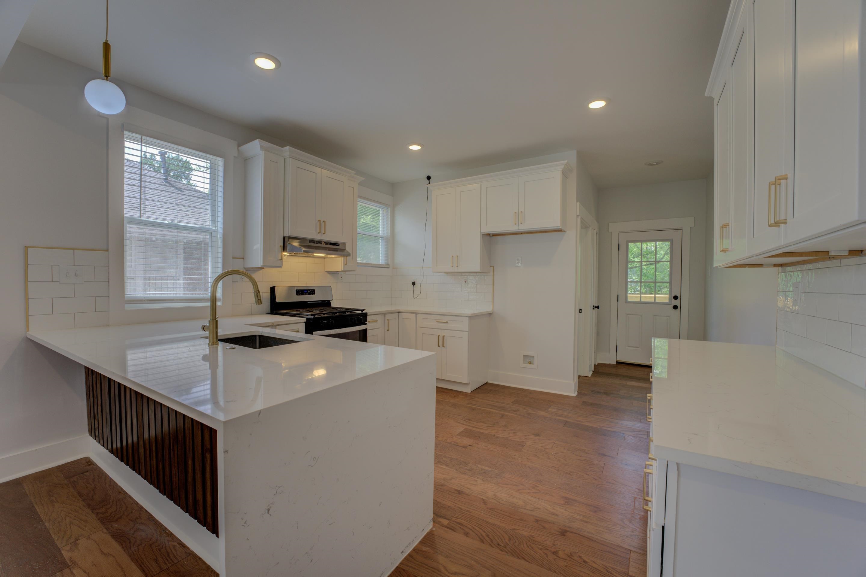 857 E Parkway South Memphis, TN 38104 - Photo 8 of 30 a kitchen with a stove a sink a refrigerator and white cabinets with wooden floor
