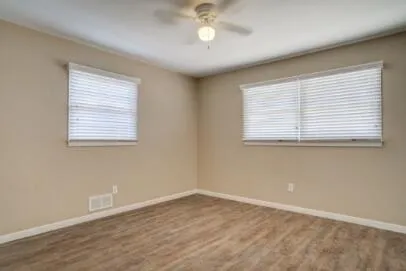 an empty room with wooden floor and windows