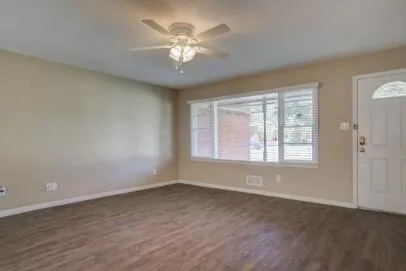 an empty room with wooden floor and windows