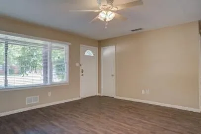 a view of an empty room with wooden floor and a window