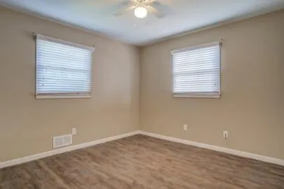an empty room with wooden floor and windows