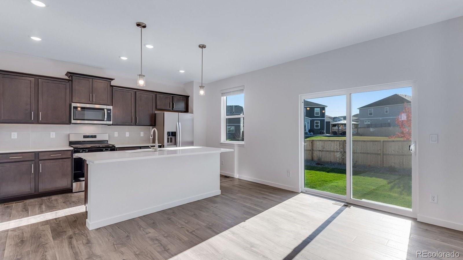 3434 Belleville Ridge Road Elizabeth, CO 80107 - Photo 23 of 48 a kitchen with stainless steel appliances kitchen island granite countertop a refrigerator a sink a stove and white cabinets with wooden floor
