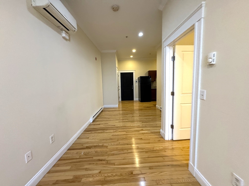 3 Main Street, Unit 201 Peabody, MA 01960 - Photo 7 of 10 a view of a hallway with wooden floor and a bathroom