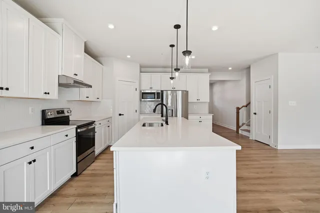 a large kitchen with stainless steel appliances kitchen island granite countertop a sink a stove and a refrigerator